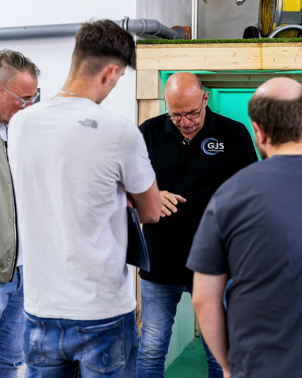 Seminarteilnehmer stehen bei der SAG-Akademie um ein Inspektionssystem herum und schauen auf die Technik
